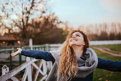 woman walking farm smiling with arms outstretched