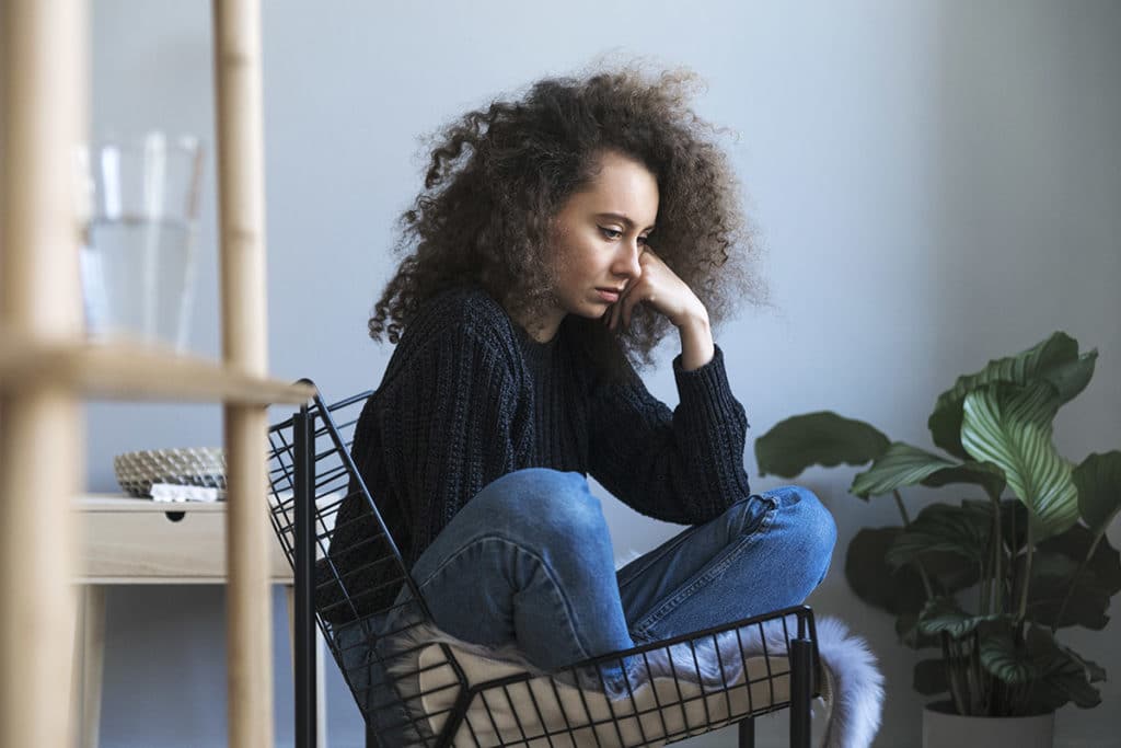 woman sitting in chair showing signs of drug relapse